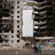 Two women walk past a apartment complex with a massive hole in its center in Ukraine.